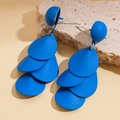 Details von geschichteten blauen Blütenohrringen auf einem minimalistischen Steinsockel - Blau
