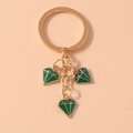 Detail of gold metal keychain with three green diamond-shaped oil-dripping pendants - Green