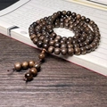 Bracelet bouddhiste en bois d'agar à 108 perles brun foncé sur un livre traditionnel - Style Perle de Tête / Modèle Ancien 8x9mm x 108 Perles