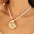 Detail of a bold golden spiral shell pendant on a white chunky woven rope necklace - Gold Conch Necklace