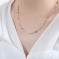 Collana in acciaio al titanio dorato con perline smaltate blu e bianche indossata da modella - Collana in smalto blu e bianco / 46cm