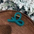 Detail of teal bow hair claw clip with golden spring on dark wooden tray over snowy background - Ribbon Style Claw