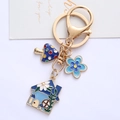 Porte-clés maison et fleurs en émail avec anneau doré sur fond blanc pur élégant - Bleu