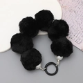Detailed view of a black plush ball phone charm with pearls and metal clasp ring - Black