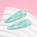Détail de deux barrettes en métal vert menthe sur un socle à texture ondulée blanche - Émeraude