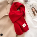 Detail of red knit scarf with emo label placed on a beige coat with a coffee cup - China Red