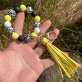 Leopard print beaded bracelet keychain with yellow tassel pendant held in hand - Yellow