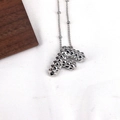 Macro shot of silver letter F pendant with faceted rivet texture on white fabric - Letter F