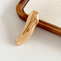 Detalle de un broche metálico dorado minimalista sobre una elegante bandeja de joyería - Dorado-Barra