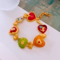 Primer plano de dijes de corazón vintage dorados con detalles de esmalte de colores - Multicolor