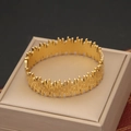 Primer plano detallado de un brazalete dorado con textura ondulada sobre un cojín de joyas - Estilo de Textura de Ondas (3#)