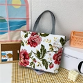 White canvas tote bag featuring large floral print and grey handles in home setting - White Floral