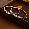 Close-up of large silver hoop earrings with clear zircons on a luxury leather box - Square Zircon Hoop Earrings
