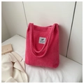 Gros plan détaillé d'un sac à main en velours côtelé rose avec étiquette tissée blanche - Rose