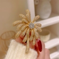 Sparkling gold firework brooch with micro-paved zircons on a white sweater - Gold