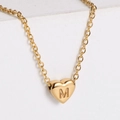Polished 18k gold plated heart necklace with initial M on a white stone background - Letter M
