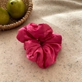 Gros plan d'un chouchou en soie rouge rose brillant sur un tissu en maille beige - Rose Rouge