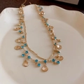 Elegante collana a doppio strato a farfalla dorata con cristalli blu su piatto di ceramica - 13# Collana con Nappine di Conchiglia e Strass a Doppio Strato