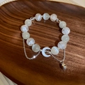 Dettaglio del bracciale di perline con ciondolo luna e pietre occhio di gatto su legno - Argento