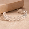 Primer plano de brazalete abierto plateado con intrincado patrón de nudo celtico hueco - Plateado