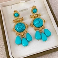 Dettaglio macro di orecchini vintage dorati con pietre turchesi in una scatola regalo - Oro-Blu (Perno per orecchini in argento)