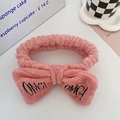 Pink plush OMG bow headband for washing face, shown on a white tabletop display - Dusty Pink
