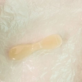 Detalle de espátula cosmética de resina amarillo crema sobre fondo de papel texturizado blanco - Albaricoque