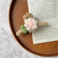 Knitted flower hair claw clip with pink center and green leaf on wooden tray - Rice White Flower