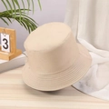 Detail of a beige cotton twill bucket hat placed on a wooden table with green plants - One Size / Khaki