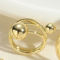 Gros plan sur la bague double anneau dorée avec des sphères métalliques géométriques - Bague à grandes et petites perles