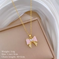 Macro detail of gold bow necklace with heart zircon pendant and pink enamel wing - A319 Titanium Steel Chain Copper Pendant