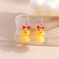 Close-up of yellow duck earrings with red bow on a white shell decorative background - Bowknot Little Yellow Duck