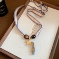 Detail of 24k gold-plated pony pendant with blue silk tassels and woven ribbon necklace - Woven Ribbon Tassel Gold Horse Necklace