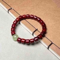 Bracelet en bois de santal avec perle lumineuse posé sur un carnet en cuir - Santal Rouge Perles Tonneau Lumineuses (8mm)