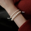 Detailed view of 4mm and 8mm pearl elastic bracelets worn on a wrist against a red background - 4+8mm Pearl Bracelet Set