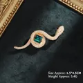 Detailed view of snake brooch with green crystal and gold metal on velvet background - Gold Snake with Green Gem (XZ24171)