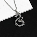 Détail macro d'un pendentif dragon en argent vintage sur une surface en pierre grise - Dragon en Forme de S