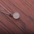 Gros plan détaillé d'un pendentif rond en pierre blanc laiteux avec chaîne en argent - Rose (Quartz rose)