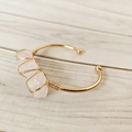 Detail of pink crystal raw stones hand-wrapped on a golden open cuff bracelet - Rose Quartz