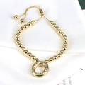 Detail of adjustable gold bead bracelet featuring a round zircon-inlaid alphabet charm - Letter O