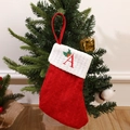 Red knit Christmas stocking featuring embroidered letter A and holly leaves on tree - Letter A