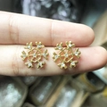 Golden snowflake stud earrings with sparkling rhinestones shown on fingertips - A138-2 Gold Snowflake
