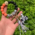 Close-up of leopard silicone bead bracelet with cow print tassel and Mama pendant - Orange Red/Cow Print (Style 13)