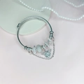 Silbernes Bettelarmband mit Herzflügeln und Kronenanhängern auf rosa Hintergrund - Silbergrau