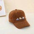 Dettaglio dei camion ricamati in stile cartone animato su un cappellino marrone per bambini - caffè