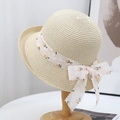 Elegant French straw sun hat with floral ribbon and bow on a wooden stand - Beige