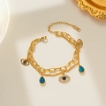 Gold-layered titanium bracelet with blue teardrop and Evil Eye charms in a luxury setup - Gold