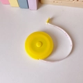 Detalle de cinta métrica retráctil amarilla con escalas de 150 cm sobre banda blanca - Amarillo