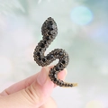 Snake brooch in gold plating featuring black rhinestones and green gem eyes - Black