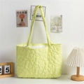 Detail of light green quilted tote bag with floral patterns and soft fabric texture - Yellow
